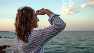 Özgürlüğün tadını çıkaran kadın. Denizin kıyısında dururken ufka bakıyor.