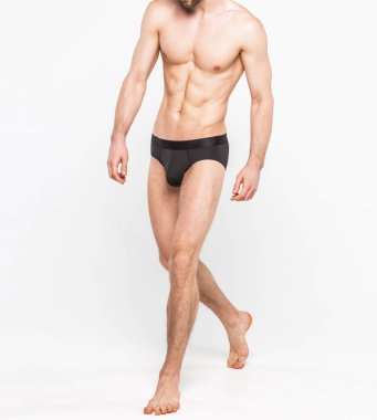 Beyaz arka planda izole edilmiş iç çamaşırı giyen kaslı genç bir adam. Erkekler için iç çamaşırı kopyalama alanı