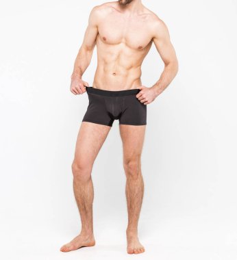 Beyaz arka planda izole edilmiş iç çamaşırı giyen kaslı genç bir adam. Erkekler için iç çamaşırı kopyalama alanı