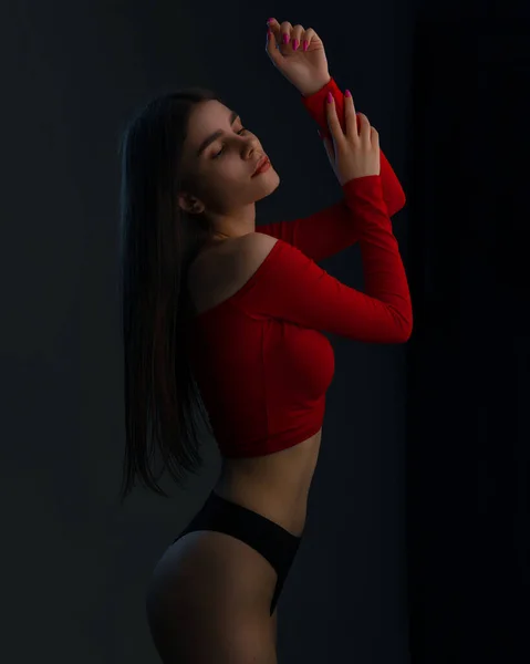 年轻女子穿着红色上衣和黑色内裤 背景是黑色的 迷人的女人完美的身材 性感的时装模特穿着黑色内裤 — 图库照片
