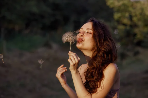 美丽快乐的女人吹大蒲公英 享受大自然 一个健康的微笑的女人在夏天的草坪上 无过敏的概念 华丽纤细的高加索语 自由的文字空间 — 图库照片