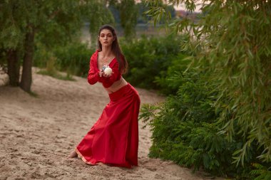 Ellerinde mumlarla ayin dansı. Göbek dansı için kırmızı kostümlü esmer kadın sahilde dans ediyor.