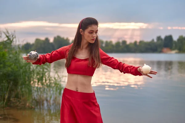 Ritual dance with candles in hands. Brunette woman in red costume for belly-dance is dancing on the beach