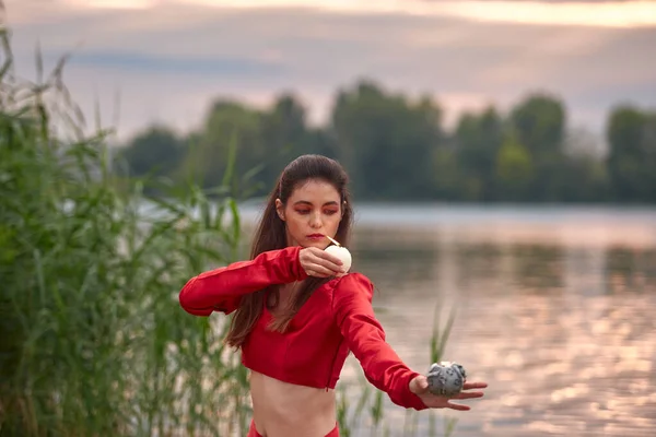 Ritual dance with candles in hands. Brunette woman in red costume for belly-dance is dancing on the beach