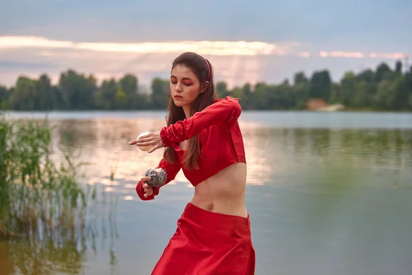 Ritual dance with candles in hands. Brunette woman in red costume for belly-dance is dancing on the beach