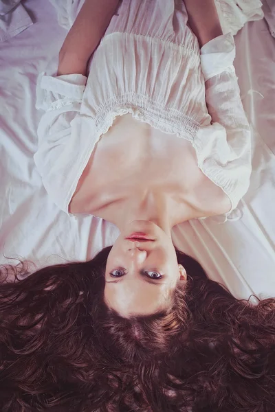 Beautiful Young woman on white dress in bed — Stock Photo, Image