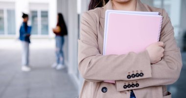 Koridorda duran bir üniversite öğrencisinin dosyasının yakın çekimi. Eğitim kavramı.