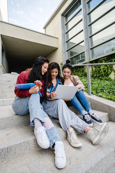 Gruppe asiatischer Studentinnen mit Laptop und gemeinsamem Lernen auf der Treppe des Universitätscampus. — Stockfoto