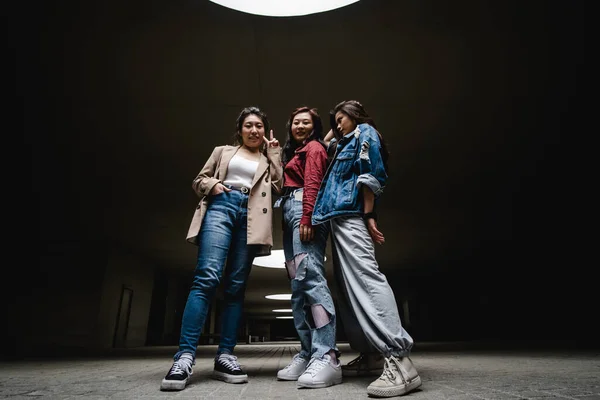 Низький кут зору групи з трьох азіатських друзів-жінки позує разом у приміщенні . — стокове фото