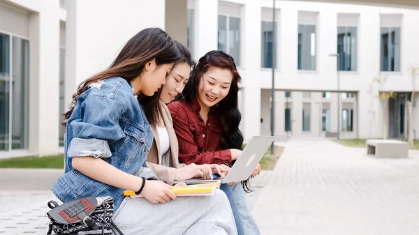 Drei asiatische Studentinnen mit dem Laptop in der Pause sitzen auf dem Campus — Stockfoto