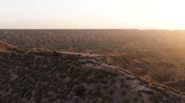Uçurumun kenarında duran yalnız bir insanın havadan görünüşü, nefes kesen kanyon manzarasına ve gün batımında altın güneş ışığına hayran.