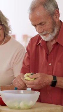 Yaşlı bir adam bir kâse salatanın üzerine elma soyarken karısı yanında duruyordu. Dikey görüntüler