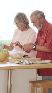 Üst düzey çift emekliliklerinin tadını çıkarıyorlar. Parlak ve modern mutfaklarında birlikte sağlıklı bir yemek hazırlıyorlar. Dikey görüntüler