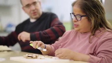 Entellektüel engelli yetişkinler yemek kursuna katılıp değerli yaşam becerileri öğreniyorlar. Bir kadın kesme tahtasındaki mantarları dikkatlice keser.