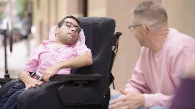 Tekerlekli sandalyede sakat bir adam bakıcısıyla canlı bir konuşma yapıyor. Serebral felçli bir adam dışarıda bir arkadaşıyla etkileşimde.