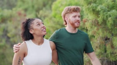 Genç melez çift konuşuyor ve birlikte gülüyorlar. Mutlu sevgili romantik bir yürüyüş yapıyor ve parkta kaynaşıyor.