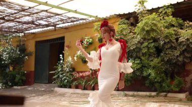 Geleneksel beyaz ve kırmızı elbiseli güzel bir kadın tutkulu bir şekilde flamenko dansı yapıyor. Tipik bir İspanyol verandasında otantik performans