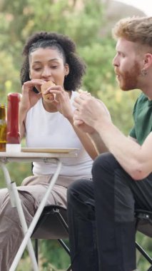 Genç, mutlu ırklar arası bir çift bir masada oturmuş kamp buluşmasında sosisli yiyor. Arkadaşlar yemeği paylaşır ve doğanın tadını çıkarırlar.
