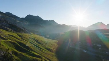 Güneş doğarken çarpıcı bir dağ manzarasının havadan görüntüsü. Güneş tepelerin üzerinde ışıl ışıl parlıyor, güzel bir mercek parıldıyor.