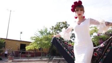 Geleneksel beyaz elbiseli tutkulu bayan dansçı dışarıda siyah bir manila şalıyla güzel ve şehvetli bir flamenko dansı yapıyor.