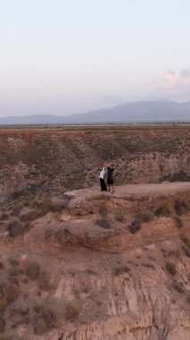 Gün batımında Gorafe Çölü 'nün tepesinden nefes kesici manzarayı kucaklayan ve tadını çıkaran genç bir çiftin hava görüntüsü.