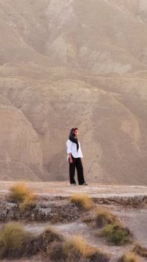 Uçurumun kenarında duran başörtüsü takan kadın Granada, İspanya 'daki Gorafe Çölü' nün geniş çorak topraklarına bakıyor.