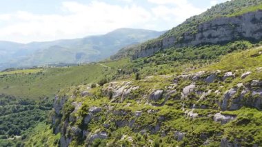 Güzel hava manzarası, nefes kesen bir dağ sırasının üzerinde zarif bir şekilde süzülen griffon akbabalarını ve yemyeşil bir vadiyi gösteriyor.