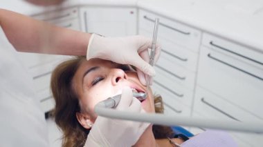 Modern bir diş kliniğinde hastaların dişlerini tedavi etmek için profesyonel aletler kullanan kadın diş hekimi. Oral sağlık ve stomatoloji kavramı