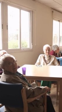 Yaşlılar evlerinin aydınlık odasındaki masalarda oturan yaşlıları yavaş çekimde büyüt