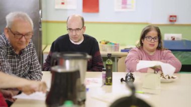 Entellektüel engelli bir grup insan bir yemek atölyesinde çalışıyor. Destekleyici bir ortamda sosyal kapsama ve beceri geliştirme