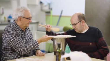 Özürlü bir adam sosyal kapsama atölyesinde yemek yapmayı öğreniyor. Bir eğitimci ona yemek hazırlamada ve günlük yaşam becerilerini geliştirmede yardımcı olur.