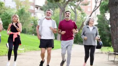 Mutlu olgun arkadaşlar parkta birlikte koşarken sağlıklı bir yaşam tarzının tadını çıkarıyorlar. Aktif son sınıf öğrencileri spor yapıyor. Spor ve refah için dışarıda.