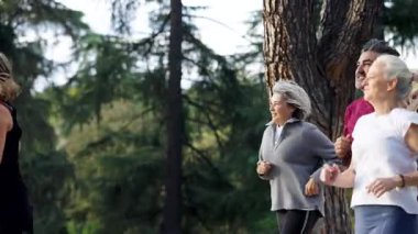 Aktif kıdemli arkadaşlar parkta birlikte koşuyorlar. Emekliliklerinin tadını çıkaran olgun erkek ve kadınlar için sağlıklı yaşam tarzı ve açık hava uygunluğu
