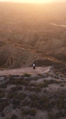 Uçurumun kenarında duran bir kadının, Granada, Endülüs ve İspanya 'nın çorak topraklarında gün batımının tadını çıkarırken görüntüsü.