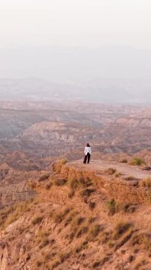Uçurumun kenarında dikilen yalnız bir kadın Granada, İspanya 'daki muhteşem çöl çorak topraklarını inceliyor.