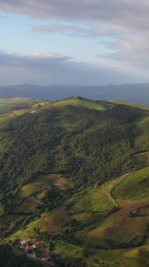 Görkemli hava manzarası, yemyeşil tepeleri, ormanları ve dolambaçlı yolları olan güzel bir vadide yuva yapmış küçük bir köy gösteriyor. Dikey görüntüler