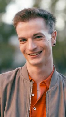 Kameraya gülümseyen genç bir adamın portresini yakından çek. Parkta duran mavi gözlü çekici ve kendinden emin bin yıllık erkek. Dikey görüntüler