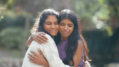 İki genç, gülümseyen Hintli bayan arkadaş ya da kız kardeş dışarıda şefkatle sarılıyorlar. Sevgisini ve sevgisini gösteren güzel bir kadın portresi