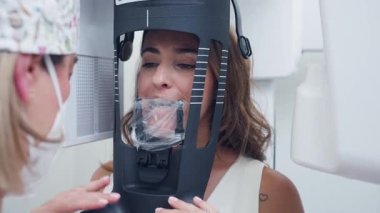 Profesyonel kadın dişçi, hastaları modern bir klinikte çene röntgeni için 3 boyutlu diş konisi tomografisine yerleştiriyor.