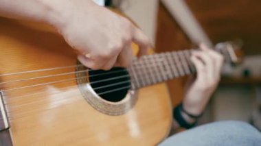 Genç müzisyenler ustalıkla akustik gitar çalarlar. Parmaklarını kapat akorları kaydet ve naylon telleri tıngırdat.