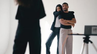 Moda fotoğrafçısı profesyonel stüdyoda beyaz arka planda birlikte poz veren iki mankeni yönetiyor.