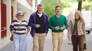 Şehir kaldırımında birlikte yürüyen dört kıdemli arkadaştan oluşan şık bir grup. Olgun erkek ve kadınlar dışarıda keyifli bir sohbetin tadını çıkarıyor.
