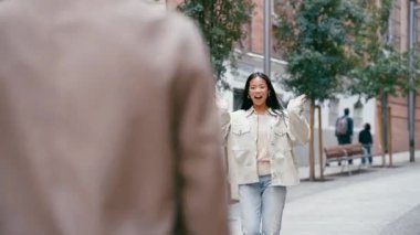 Dört farklı genç arkadaş birbirlerini gülümseme ve sıcak kucaklaşmalarla sevinçle selamlıyorlar. Kentsel bir sokakta buluşan kadın ve erkeklerin bir araya gelişi.