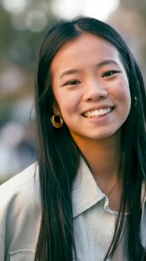 Kameraya gülümseyen uzun siyah saçlı neşeli Asyalı bir kadının portresini yakından çek. Doğal güzellik ve olumlu duygu kavramı. Dikey görüntüler