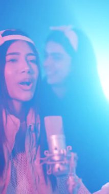 Tutkulu genç bir kadın profesyonel bir kayıt stüdyosunda şarkı söylüyor. Bu yetenekli sanatçı yoğun bir mikrofona duygu dolu bir şekilde şarkı söylüyor. Dikey görüntüler