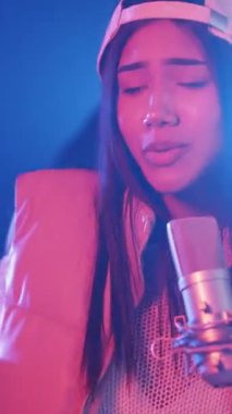 Yetenekli bayan şarkıcı tutkuyla bir kayıt stüdyosunda şarkı söylüyor. Genç sanatçı, neon ışıkları olan profesyonel bir mikrofona vuruyor. Dikey görüntüler