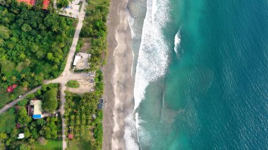 Kosta Rika kıyıları yemyeşil ormanlarla dolu kumlu bir sahil ve turkuaz okyanus dalgalarıyla buluşuyor. Tropik cennet gökyüzü manzarası