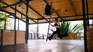 Açık hava stüdyosunda çift antreman direği dansı. Tropikal bir ortamda güç, zindelik ve ortaklık göstergesi.