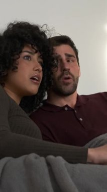 Hafta sonu evlerinde korku filmi seyrederken rahat koltukta mısır yiyen ürkek genç bir çift.