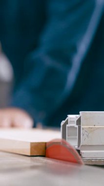 Profesyonel bir marangozun ahşap bir tahtayı kesmek için testereyle kestiği yakın plan görüntüsü. Keskin bıçak keresteyi keserken talaş uçar. Dikey